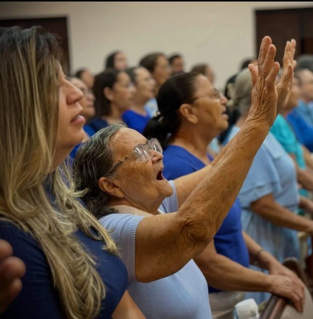 Irmãs levantando as mãos em louvor