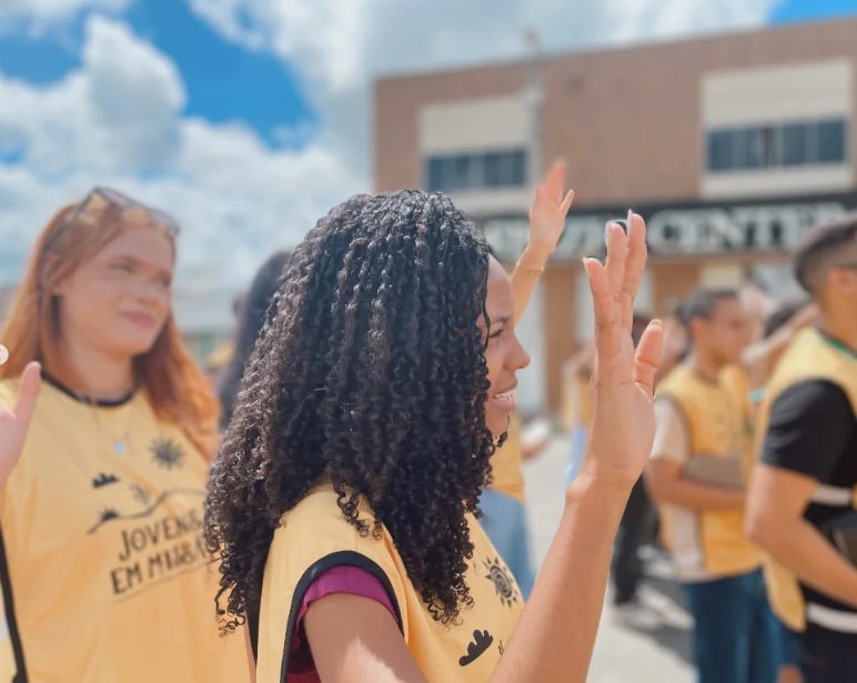 Jovem missionária de mão levantada na rua