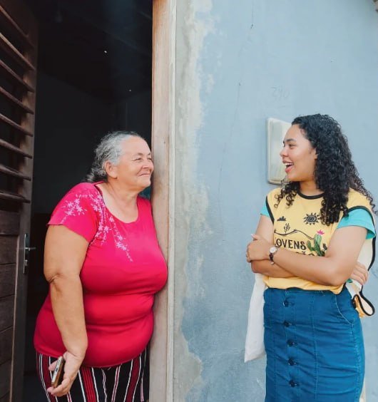 Irmãs conversando numa porta de casa durante a visita